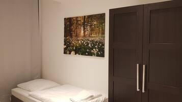 A bedroom with a bed, a wardrobe, and a wall-mounted picture of a forest scene.
