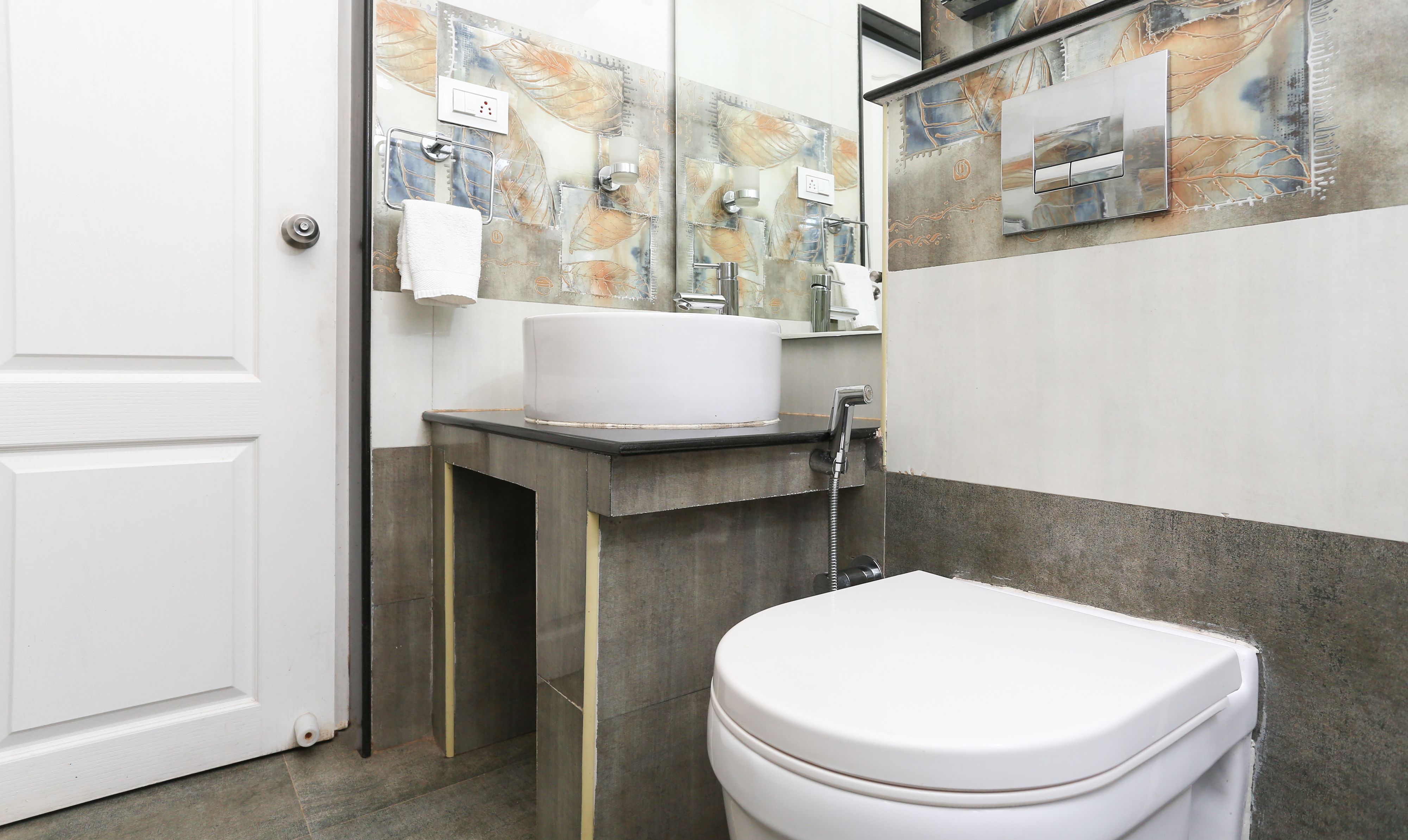 A modern bathroom with a white toilet, a sink with a mirror above it, and a decorative wall.