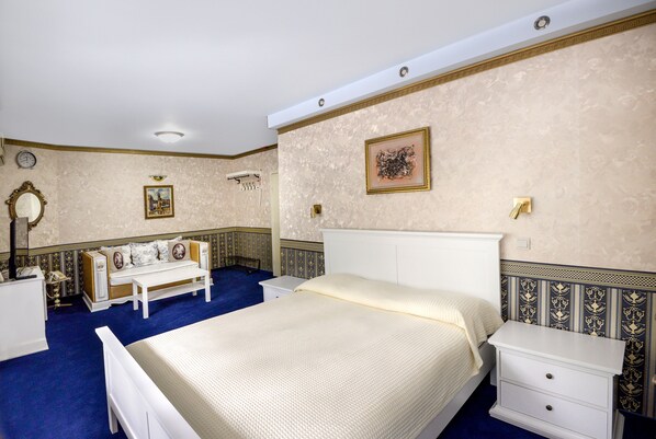 A bedroom with a bed, bedside tables, a bench, a mirror, and decorative wall panels.