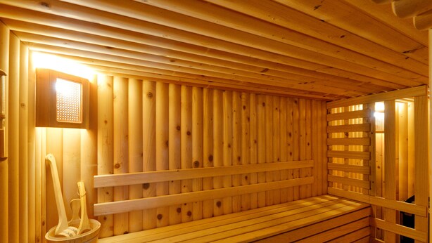 Un sauna en bois, doté de bancs et d’un seau contenant des outils en bois.