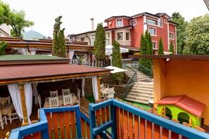 A colorful outdoor area with a wooden deck, a small playhouse, and a restaurant with outdoor seating.