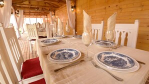 Une longue table à manger, dressée avec de la vaisselle bleue et blanche, des couverts en argent et des serviettes pliées.