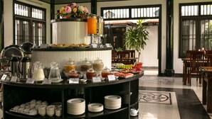 A buffet setup with various food items and beverages, including fruits, pastries, and a coffee station. - Hoian Nostalgia Hotel & Spa (Da Nang)