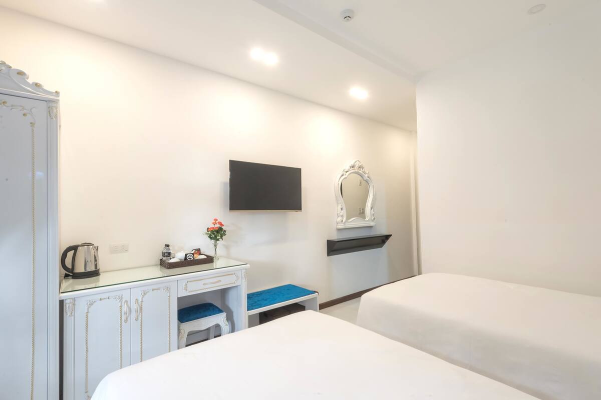 A hotel room with a bed, a desk with a chair, a television, and a mirror.