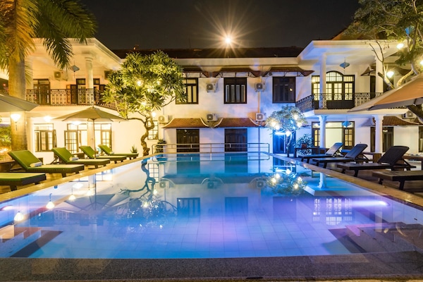 Una piscina al aire libre, sombrillas, sillones reclinables de piscina