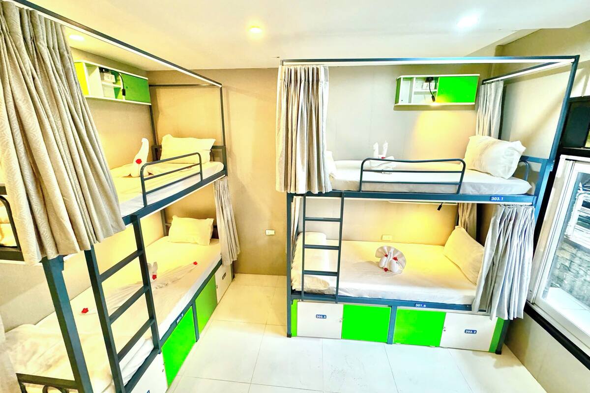 A bunk bed room with a small window, a green and white color scheme, and a built-in shelf.