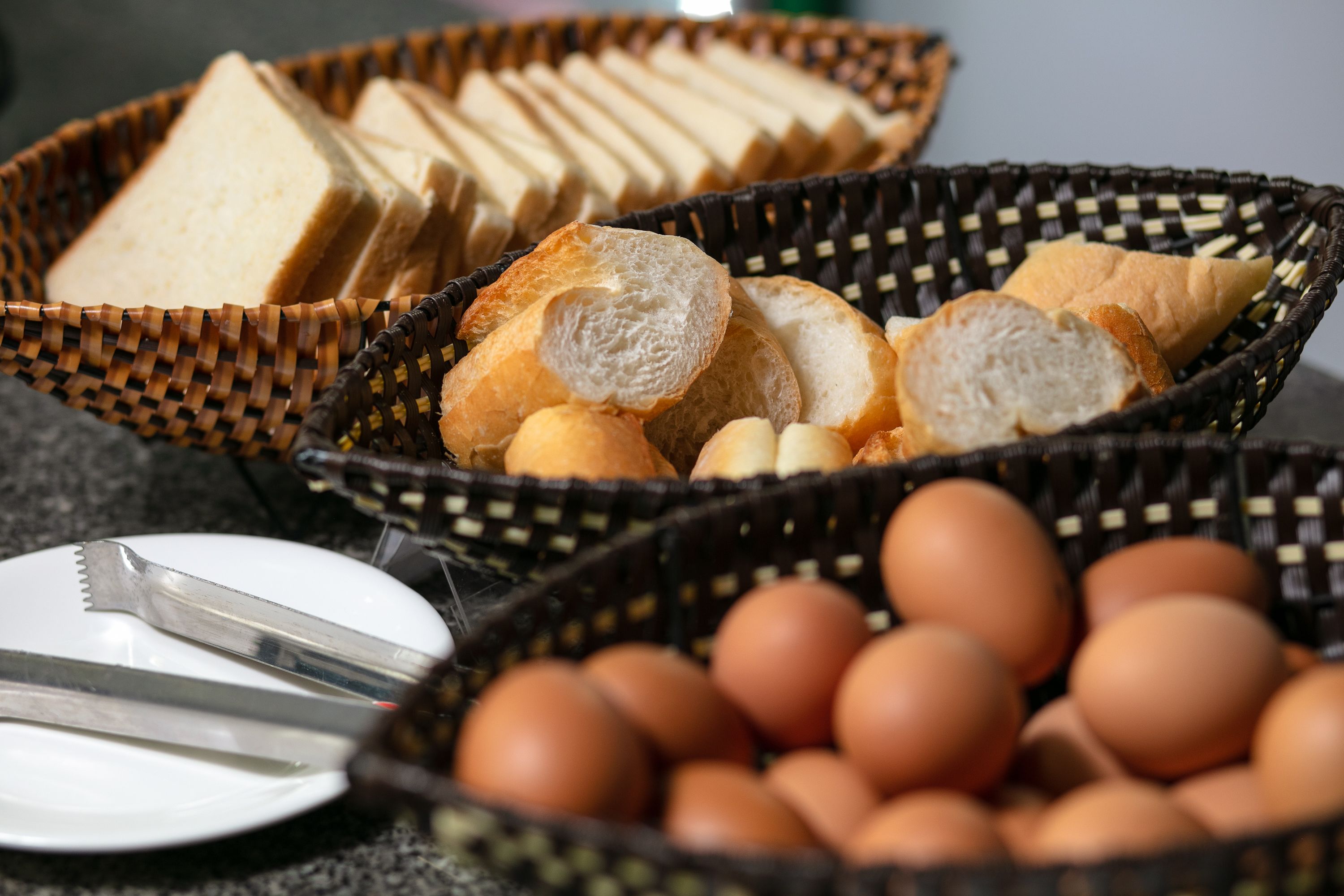 Two wicker baskets containing sliced bread and eggs.