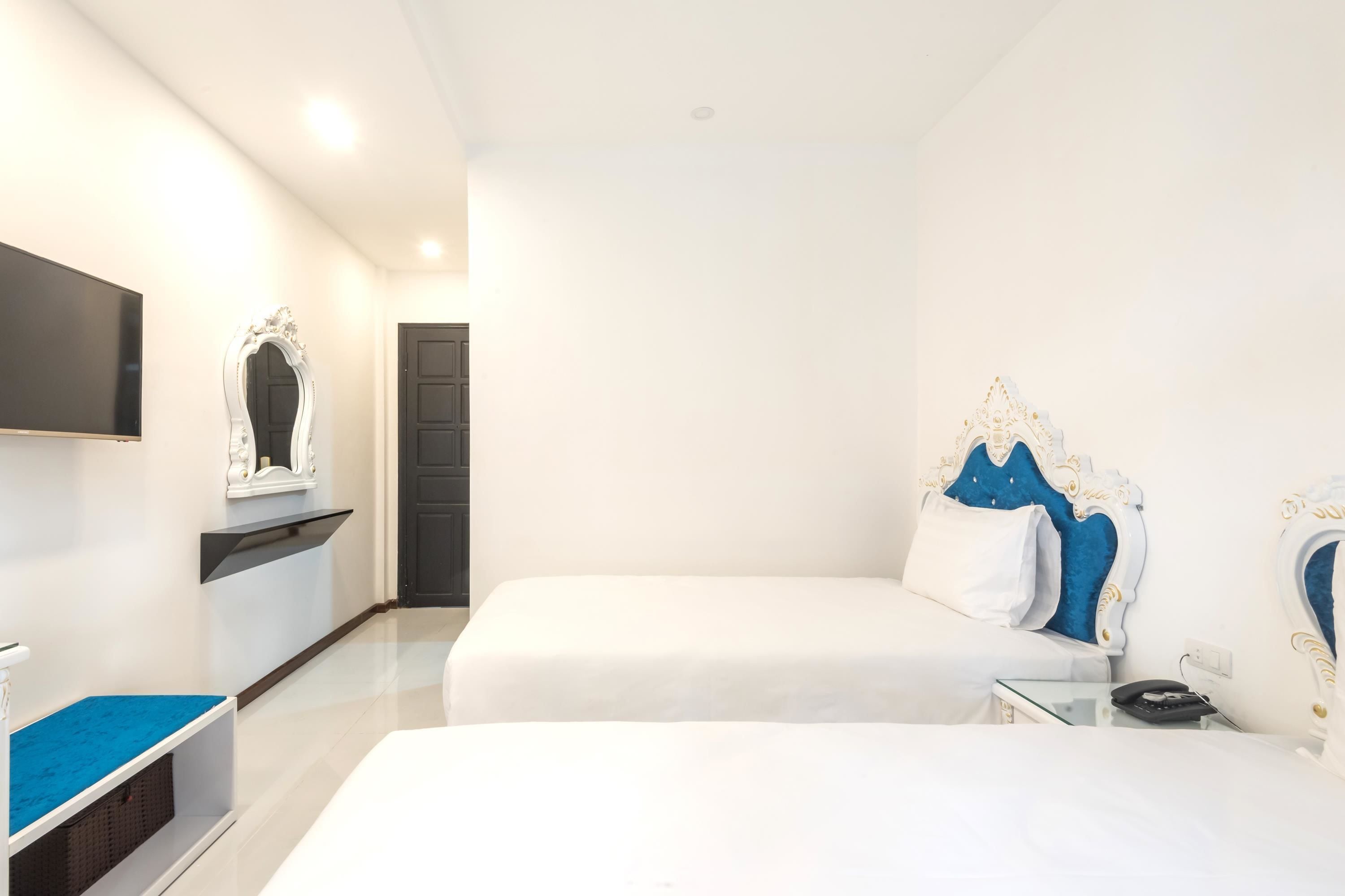Une chambre d’hôtel moderne équipée de deux lits, d’un téléviseur à écran plat, d’une petite table et d’un miroir décoratif.