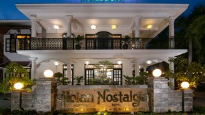 A hotel facade with a sign reading "Holi Nostalgia Hotel & Spa" and a stone entrance with a neon sign. - Hoian Nostalgia Hotel & Spa (Da Nang)