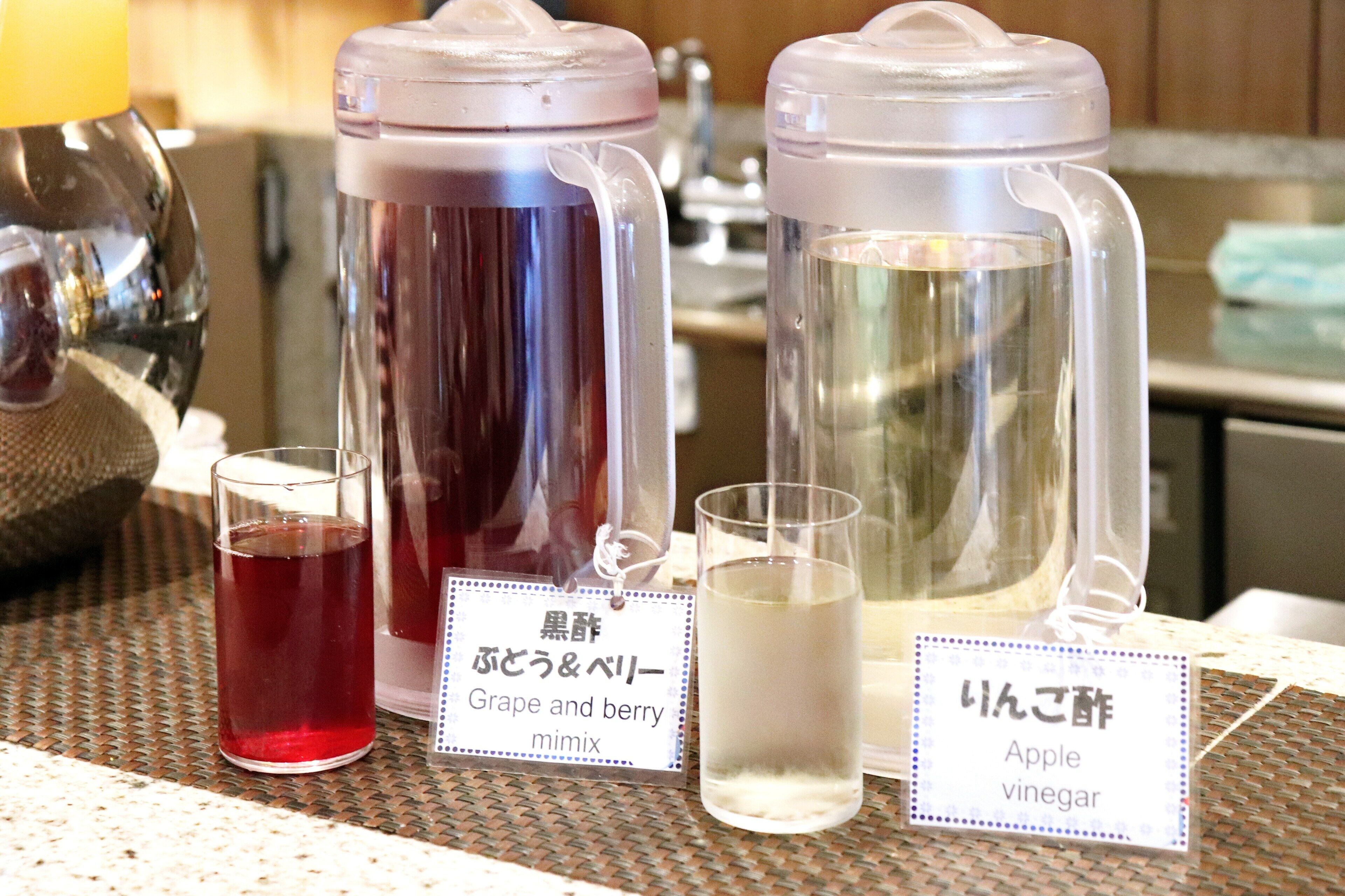 Dos recipientes de vidrio con etiquetas, uno con la etiqueta 'Grape and berry mimix' y el otro 'Apple vinegar'.