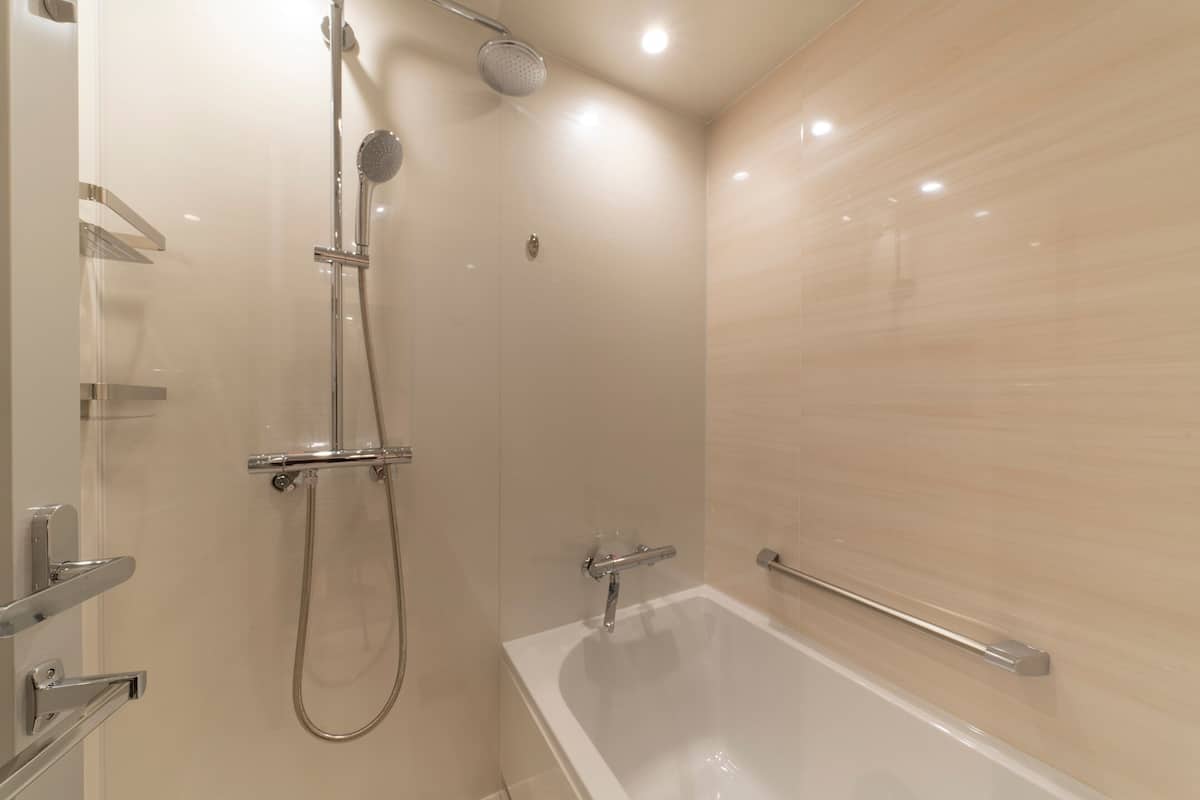 Une salle de bain moderne dotée d’une douche à parois de verre, d’une baignoire sur pieds et de toilettes équipées d’une barre d’appui.