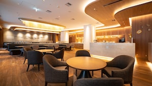 A modern restaurant with round tables and chairs, a kitchen area, and wooden accents. - Hotel JAL City Nagoya Nishiki (Nagoya)