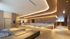 A modern hotel lobby with a reception desk, seating area, and a kitchen in the background. - Hotel JAL City Nagoya Nishiki (Nagoya)