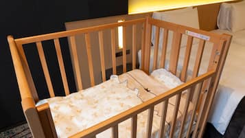 Cozy sleeping area with a crib and a bed, featuring a safety notice for added peace of mind.