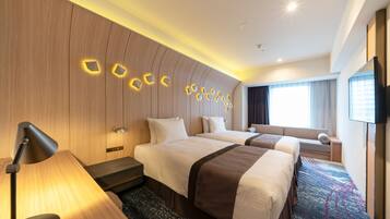 A hotel room with two beds, a desk, a lamp, a TV, and a window with curtains.