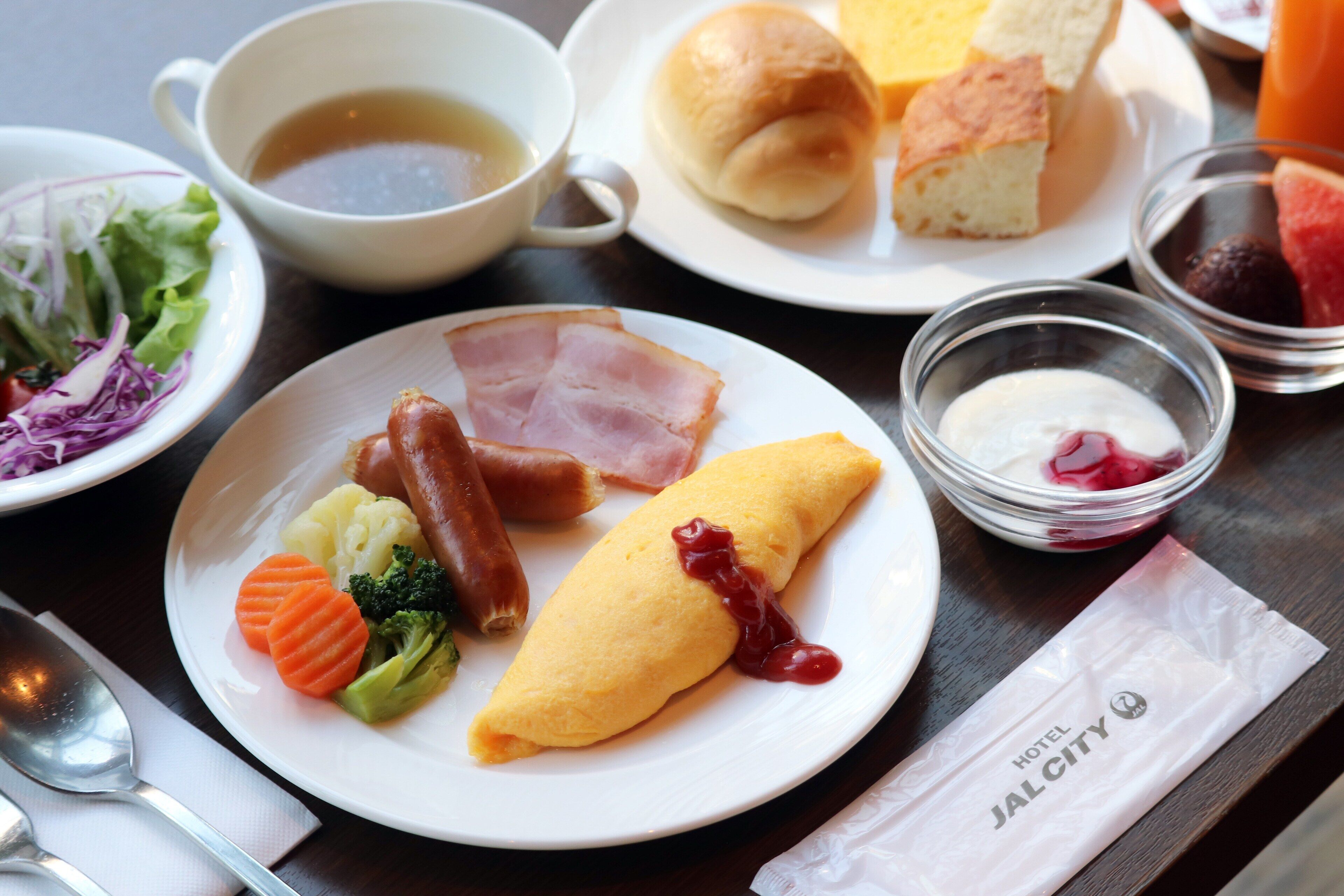 A plate with ham, a rolled omelette, and vegetables.