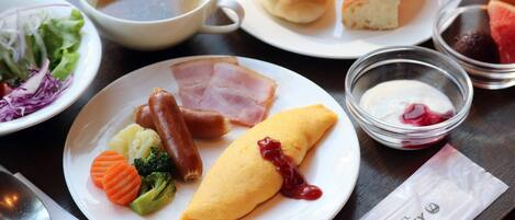 A plate with ham, a rolled omelette, and vegetables.