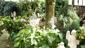 A garden with a statue of an angel, a white lantern, and a bench. - Am Glockenturm (Luechow)