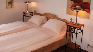 A double bed with a wooden headboard, two bedside tables, and a lamp on each side. - Am Glockenturm (Luechow)