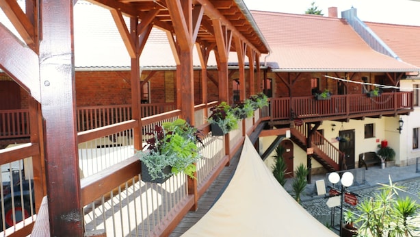 A wooden balcony with railings and potted plants.