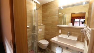 A bathroom with a shower, toilet, sink, and mirror.