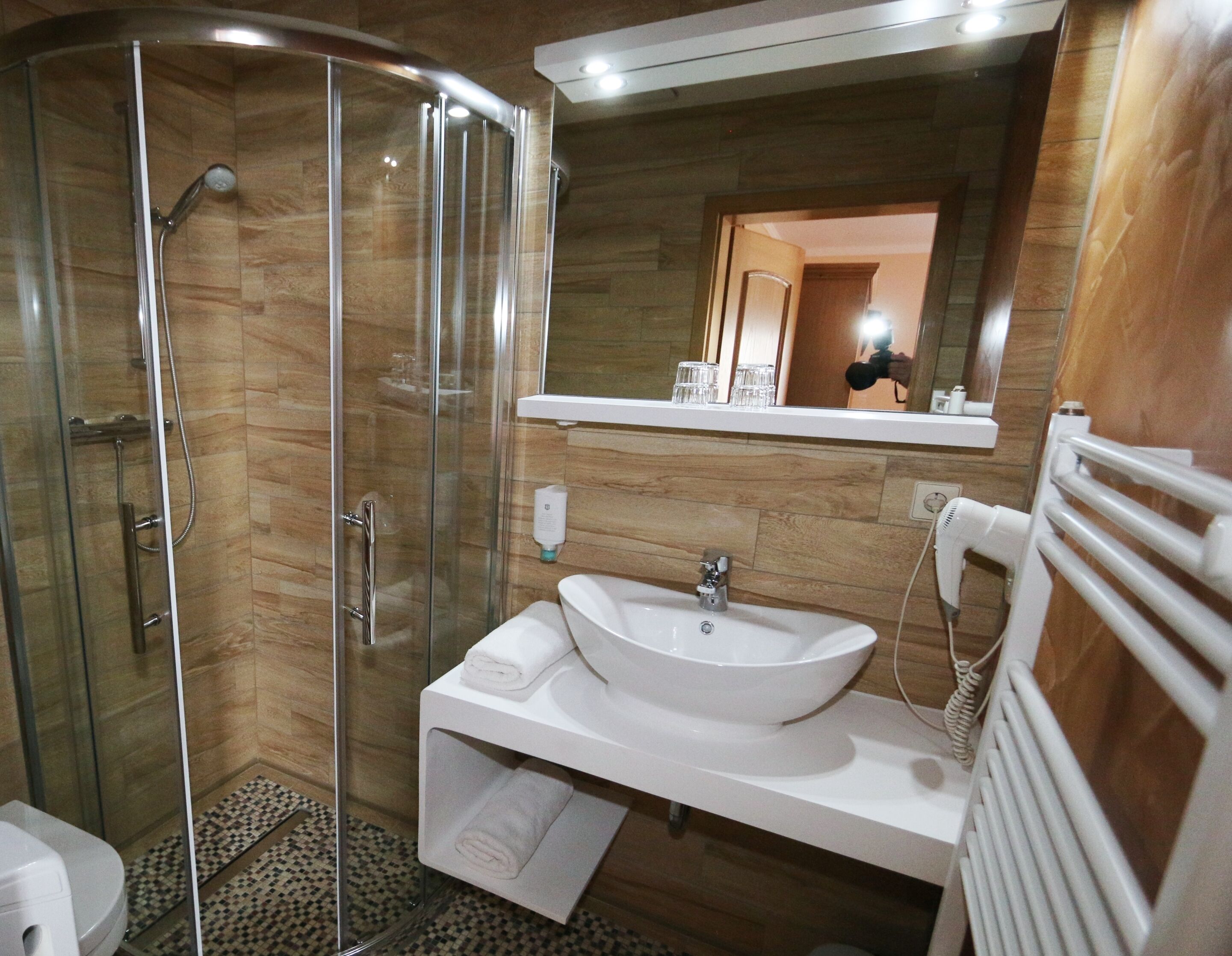 A modern bathroom with a glass-enclosed shower, a white sink, and a mirror above the sink.