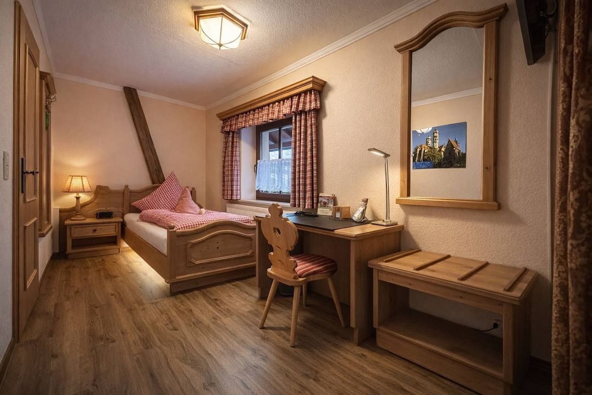 Een slaapkamer met een houten bed, een bureau, een stoel en een grote spiegel.