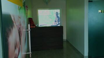 Zona de recepción de un spa con una estatua de Buda, un cartel grande del spa y un mostrador de recepción.