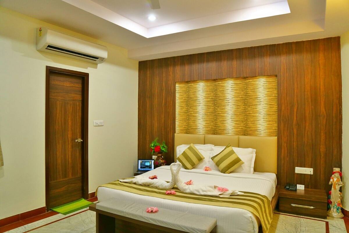A bedroom with a bed, bedside table, nightstand, and an air conditioning unit.