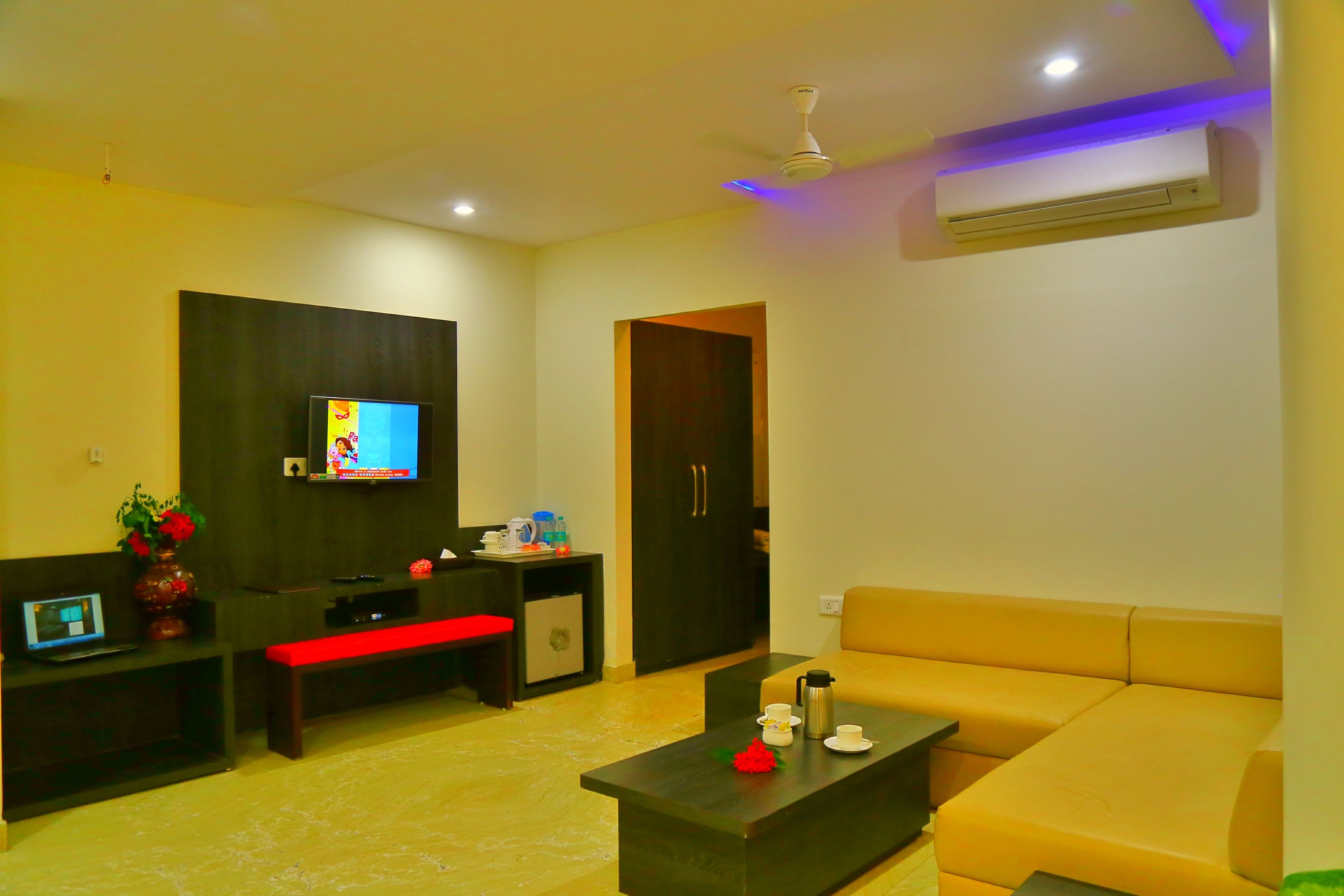 A modern living room with a sofa, a coffee table, a TV, and a small kitchenette area.