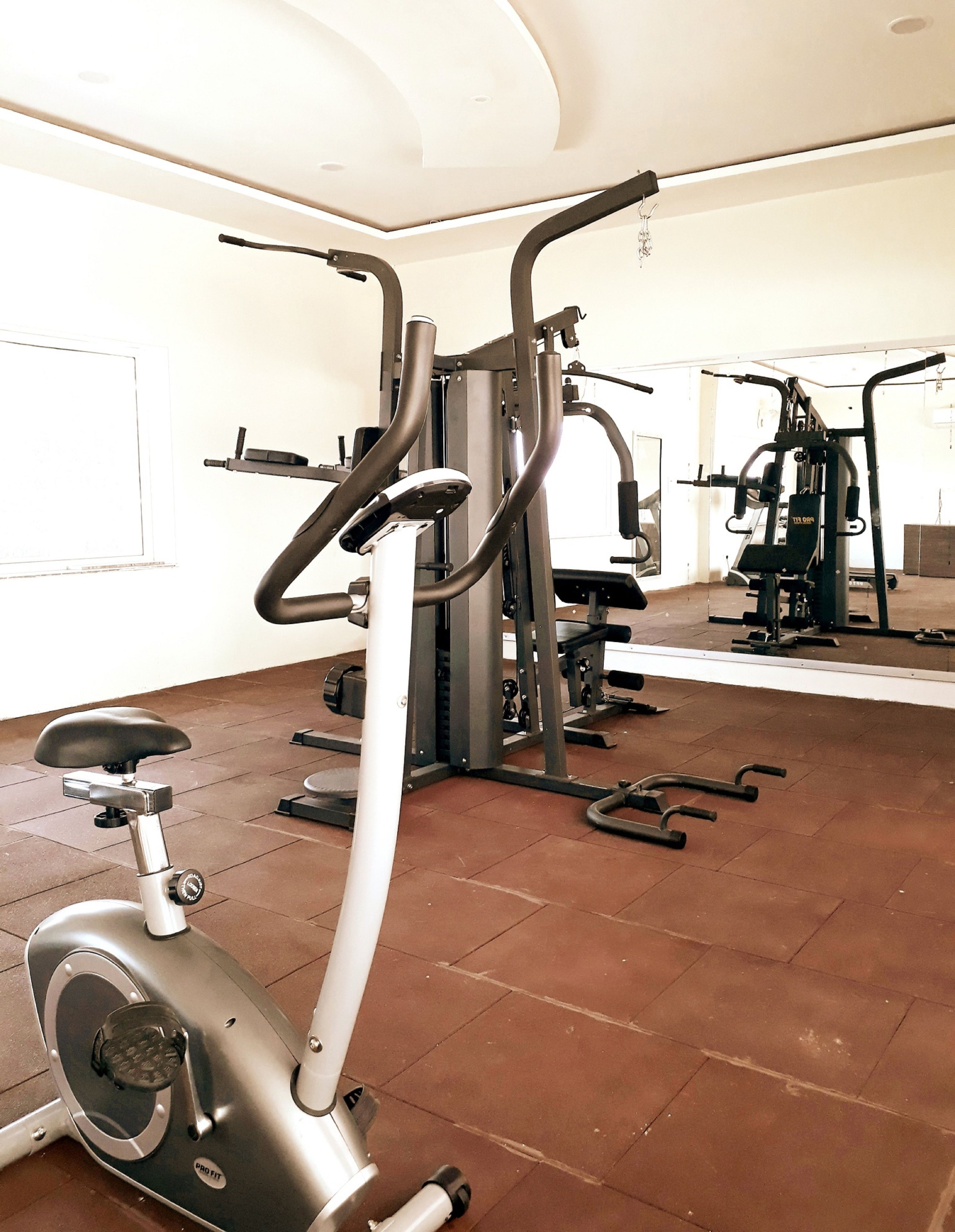 A gym with exercise equipment including an elliptical trainer, a cable machine, and a bench press.