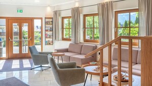 Een moderne hotel lobby met een bank, stoelen, een tafeltje en een trap.