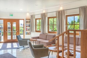 Un moderno vestíbulo de hotel con un sofá, sillas, una mesita y una escalera.