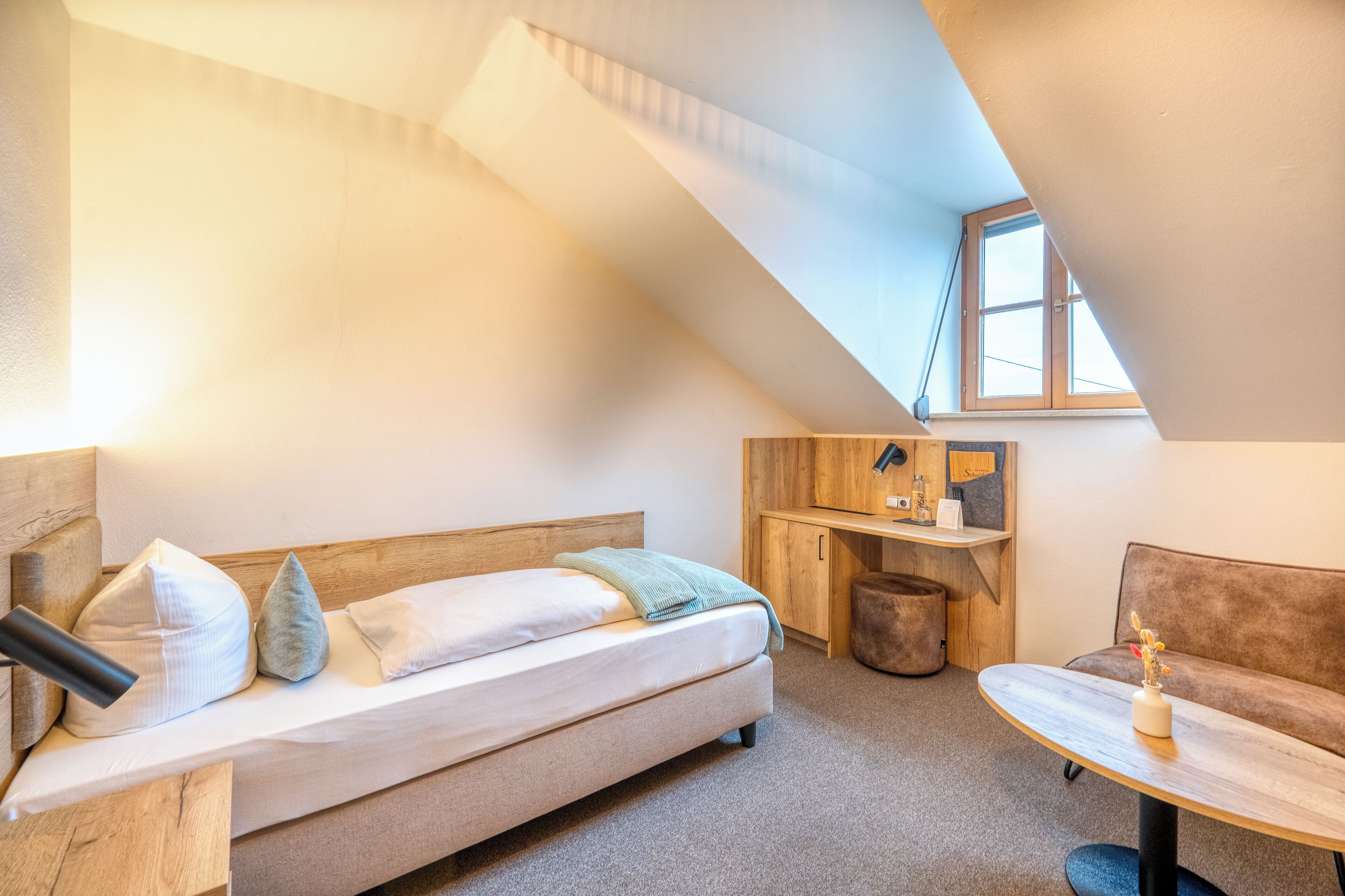 A cozy room with a bed, a small table, a sofa, and a desk.