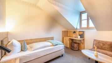 A cozy room with a bed, a small table, a sofa, and a desk.