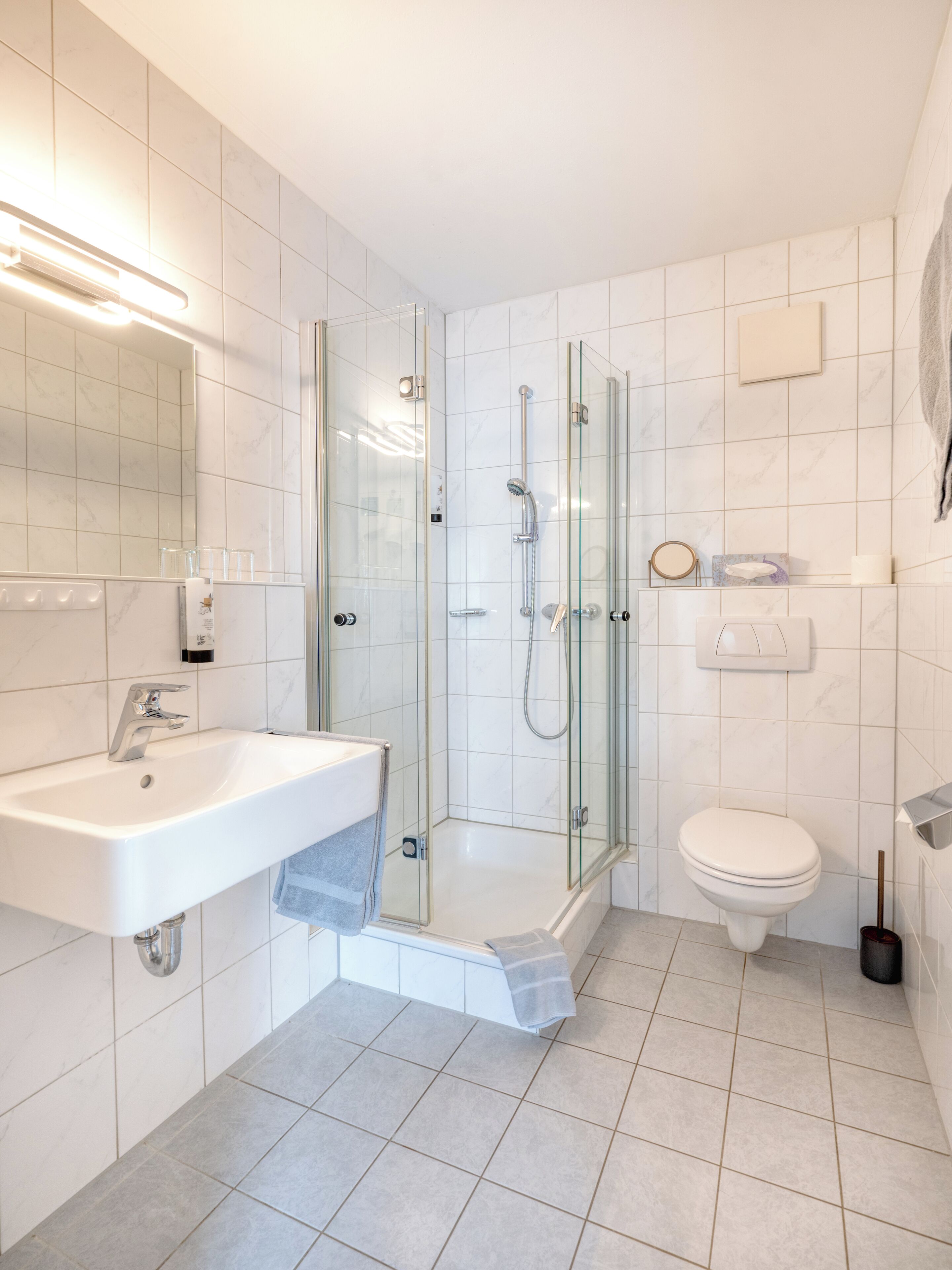 Ein modernes Badezimmer mit einer Duschkabine, einem weißen Waschbecken und einer Toilette.