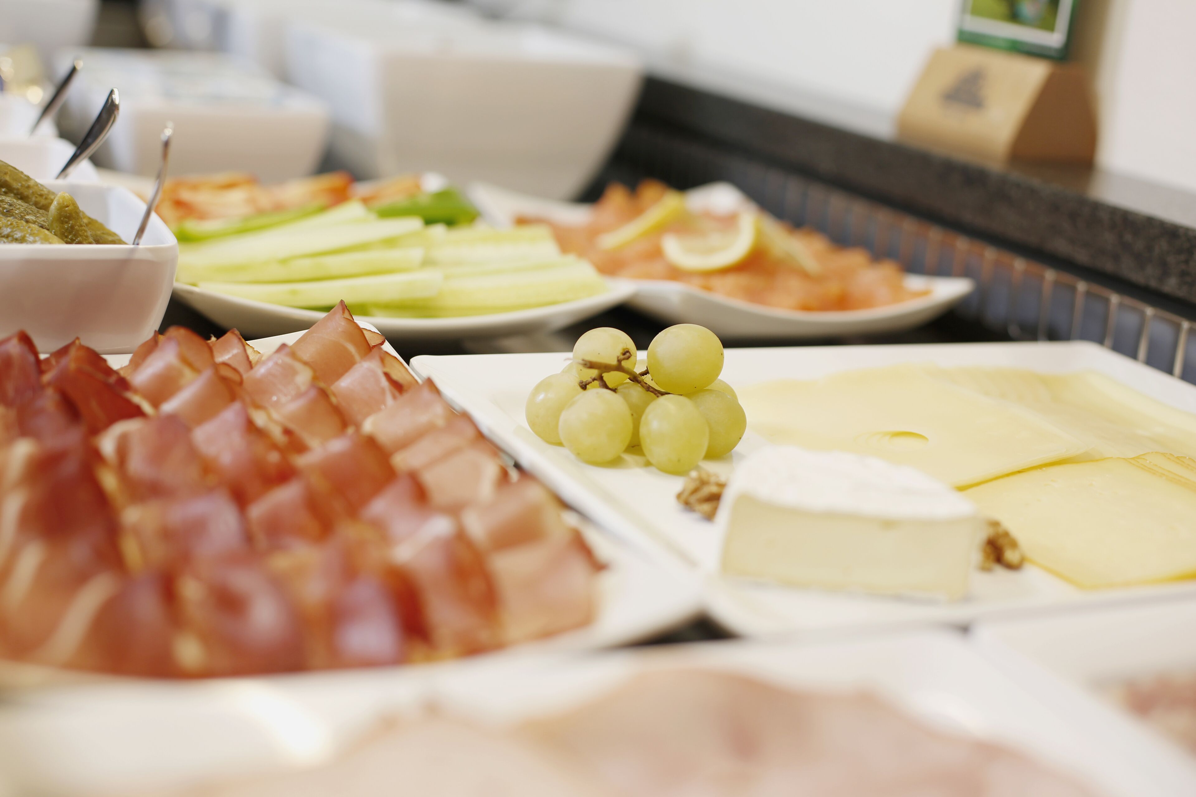A buffet with various food items including meats, cheeses, and fruits.