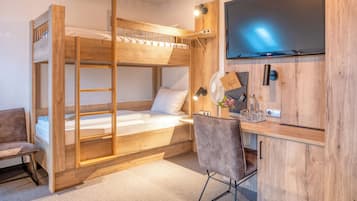 Ein Stockbett mit Schreibtisch und Stuhl, einem Flachbildfernseher und einem kleinen Schrank mit Ventilator und Dekoration.