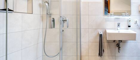 Een moderne badkamer met een douche met glazen wand, een wastafel en een spiegel.