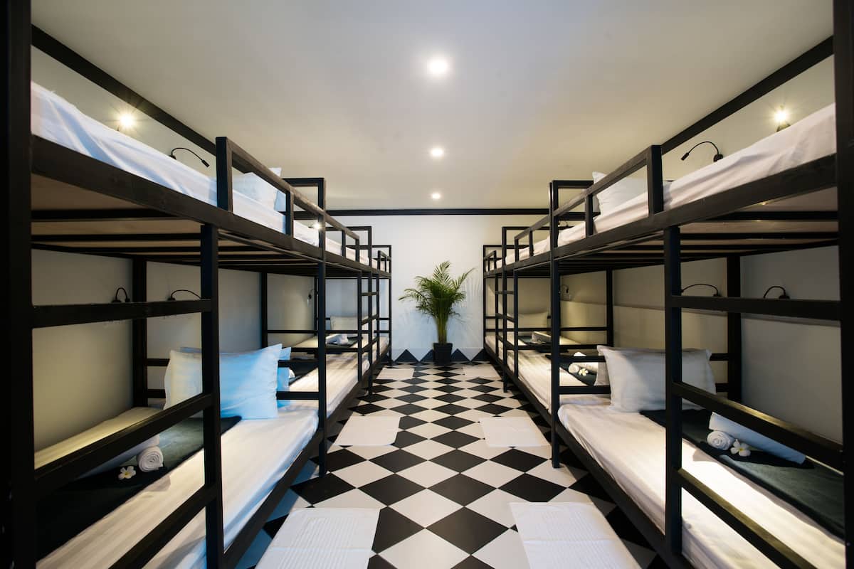 A room with bunk beds, a checkered floor, and a potted plant in the center.
