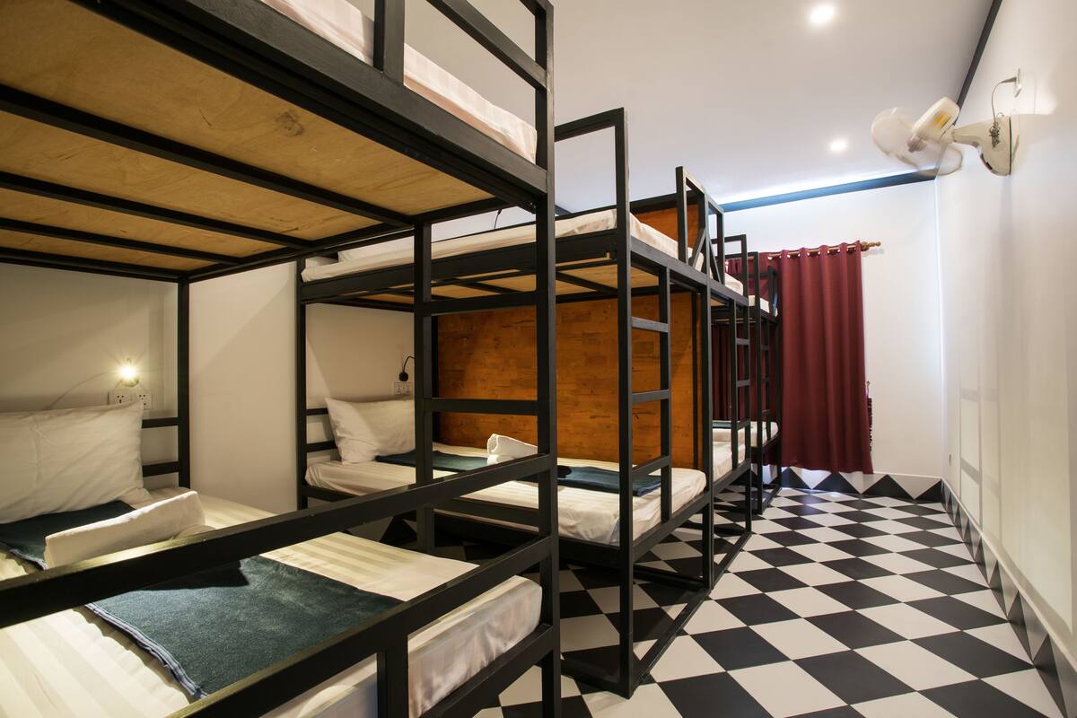 A bunk bed room with a checkered floor and a red curtain.