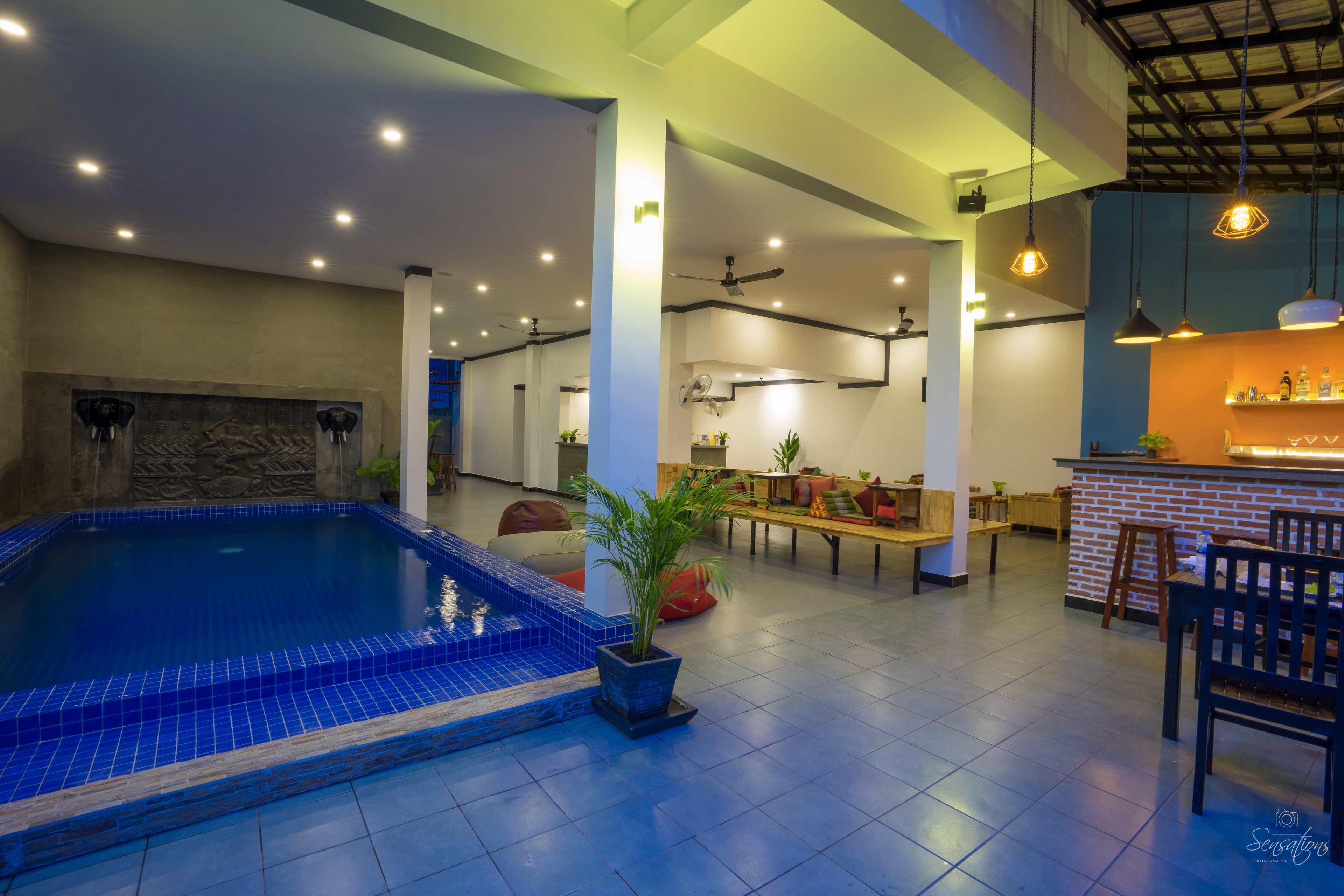 Un espacio interior amplio con piscina, zonas de estar y un bar.