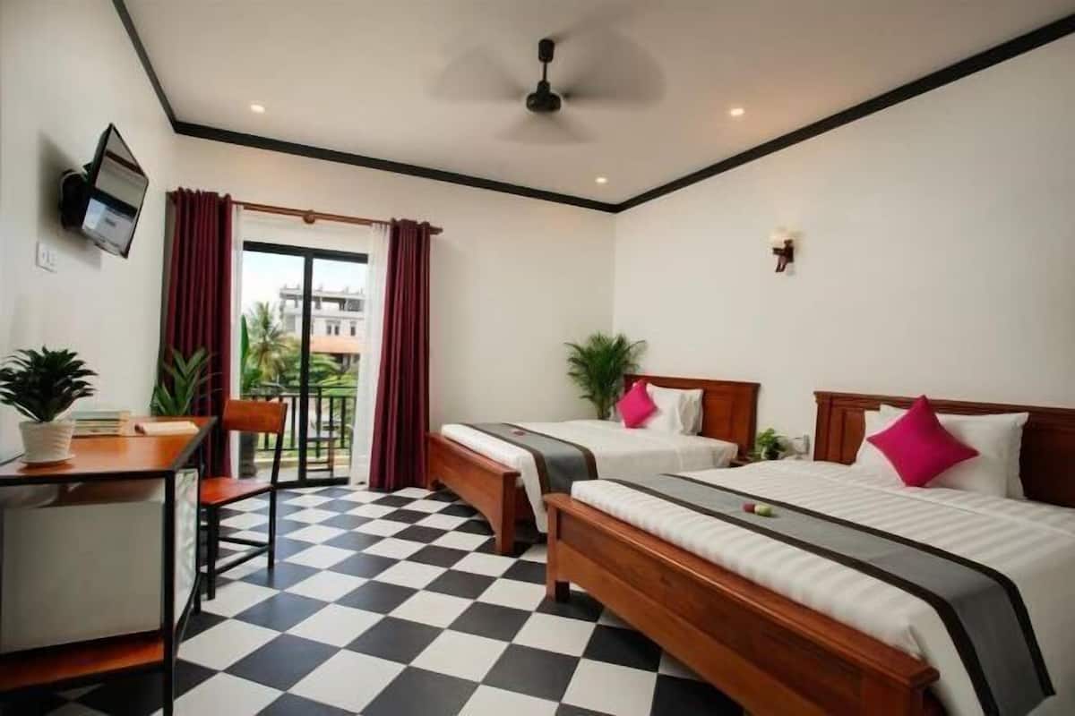 A hotel room with two beds, a desk, a chair, a TV, and a balcony with red curtains.