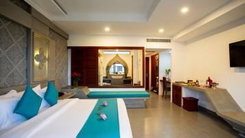 Une chambre d’hôtel avec un grand lit, un petit bureau et une salle de bain visible à travers une porte en arc de cercle.