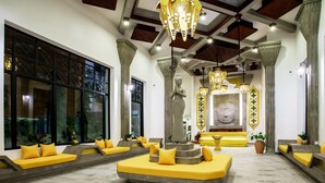 Un interior moderno con un área de estar central, ventanas amplias y columnas decorativas.