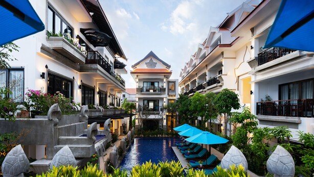 Un patio de hotel con piscina central, rodeado de exuberante vegetación y arquitectura moderna.