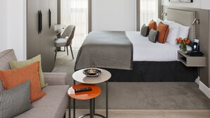 Una habitación de hotel moderna con una cama, un sofá, una mesita pequeña, un ventilador de techo y un escritorio.