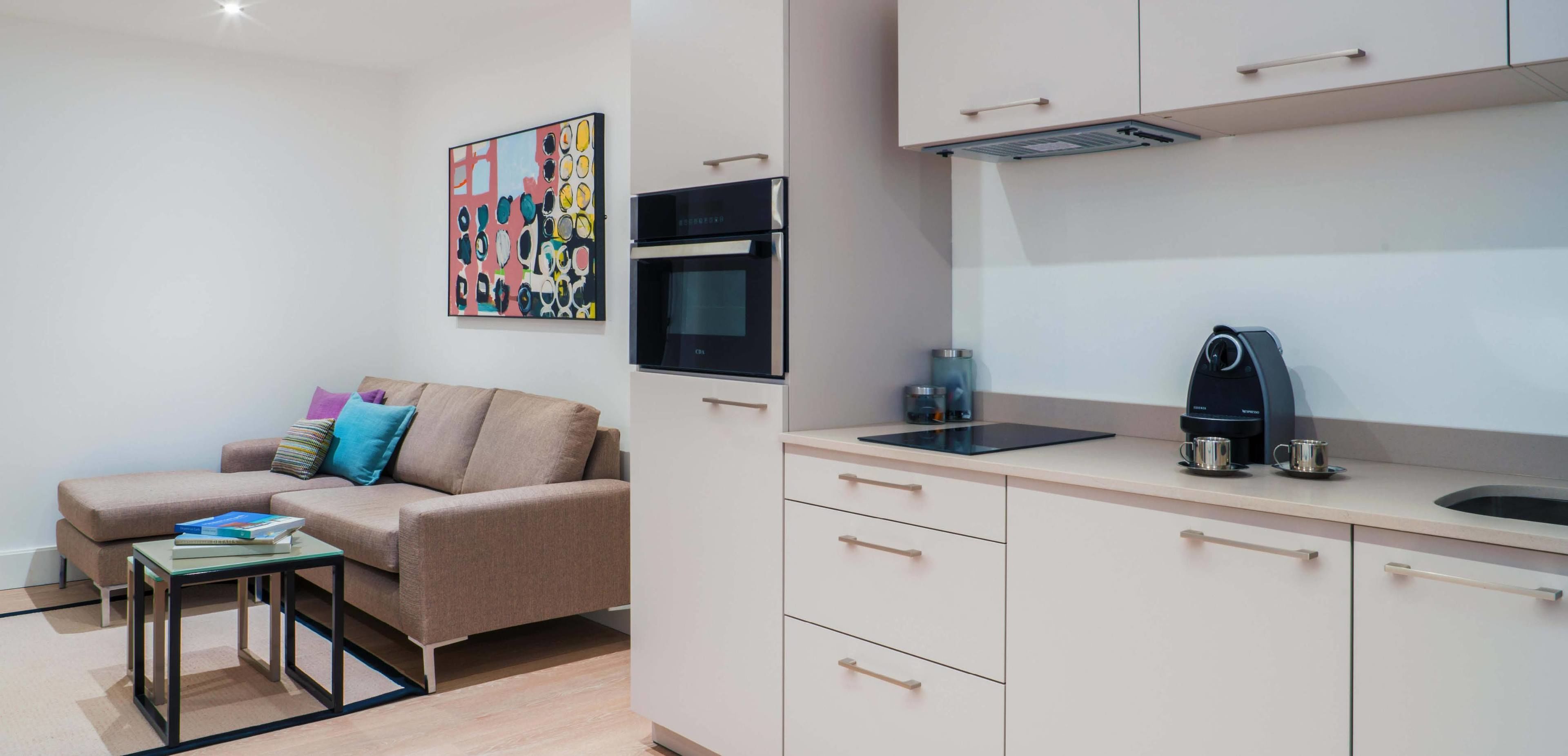 A modern kitchen with a built-in oven, a coffee machine, and a tablet on the counter.