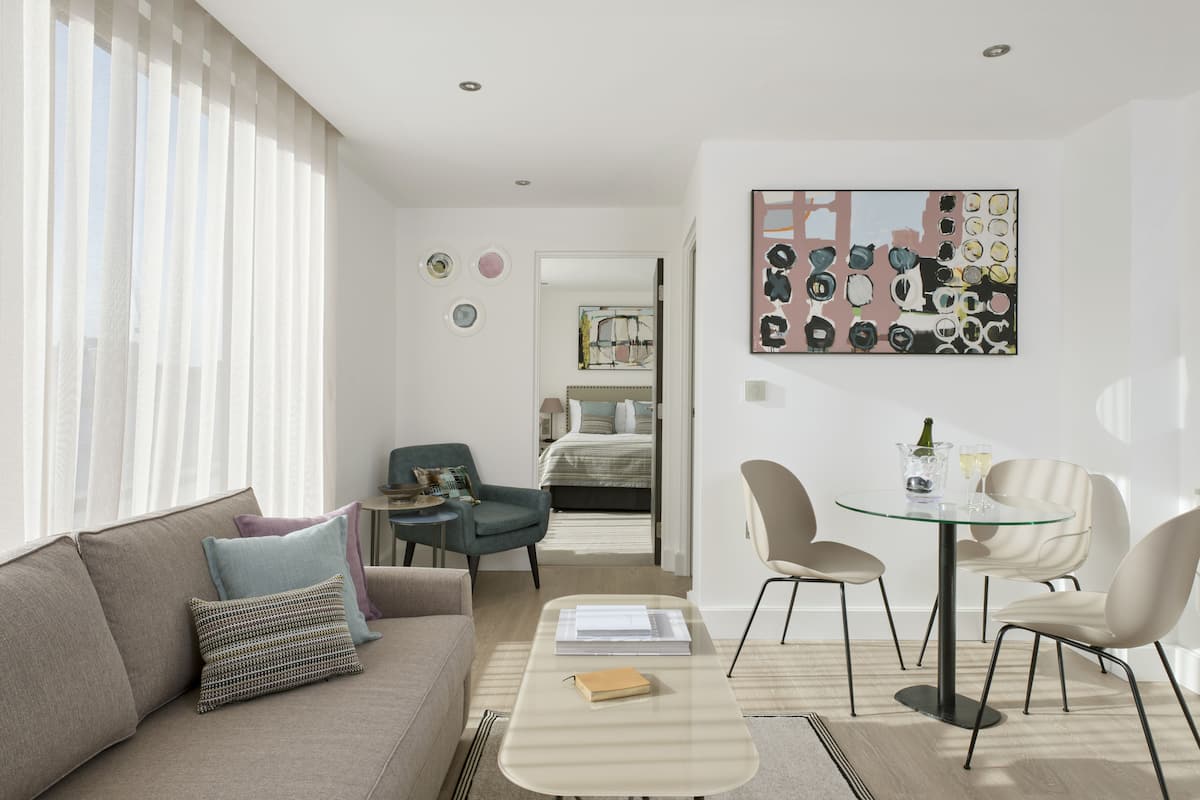 Una sala de estar moderna con un sofá, sillas, una mesa de centro y una zona de comedor con una mesa y sillas.
