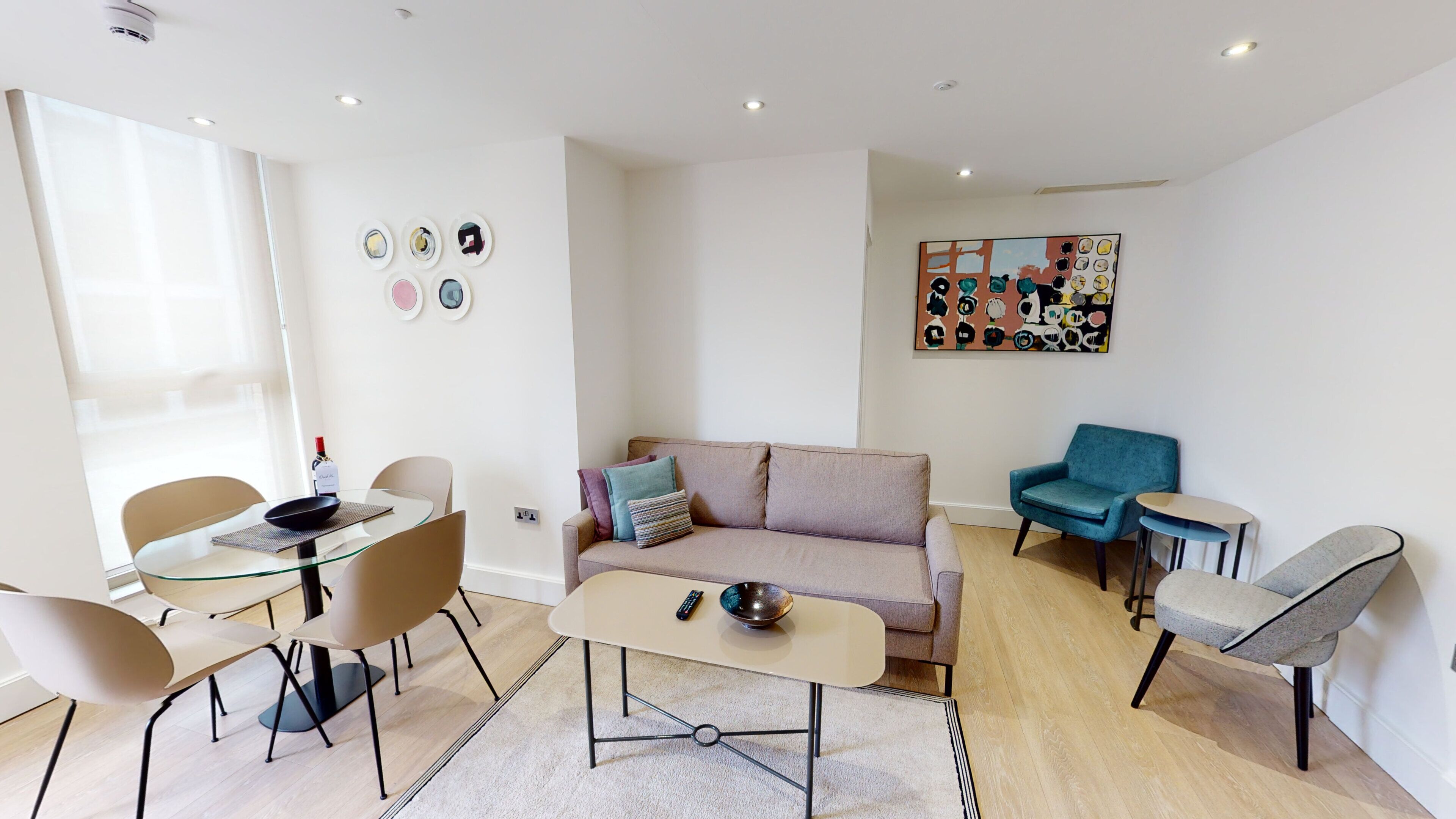 Un salon moderne comprenant un canapé, une table basse et un coin repas avec des chaises et une table en verre.